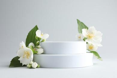 Photo of Beautiful jasmine flowers with leaves on light background. Space for text