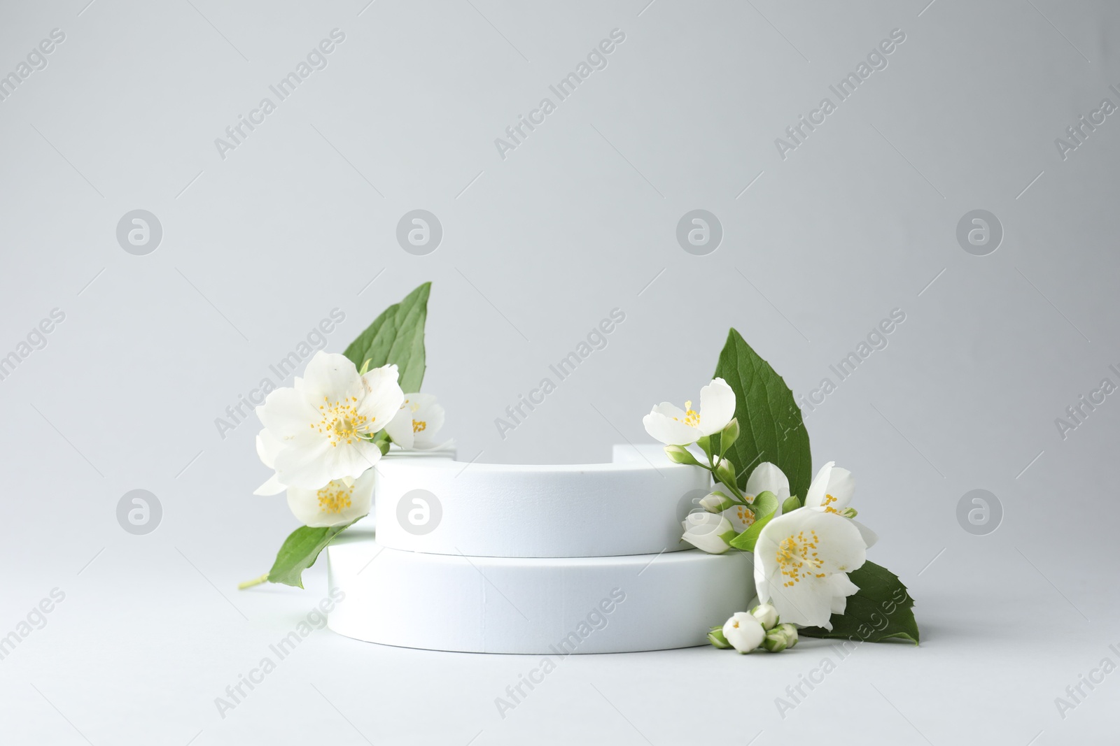 Beautiful jasmine flowers with leaves on light background. Space for text Photo of Beautiful jasmine flowers with leaves on light background. Space for text