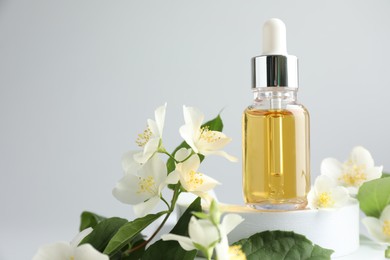 Photo of Cosmetic product and jasmine flowers on light background, closeup. Space for text