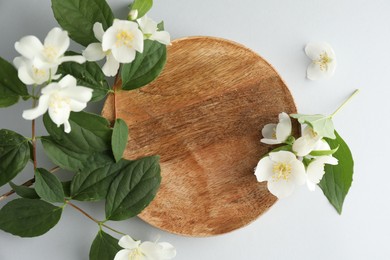 Photo of Beautiful jasmine flowers with leaves on light background, flat lay