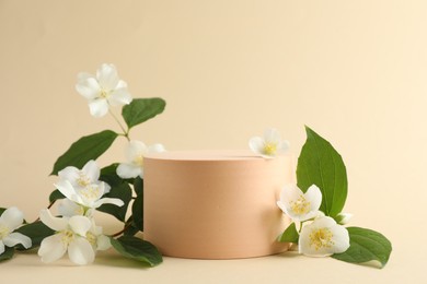 Photo of Beautiful jasmine flowers with leaves on beige background. Space for text