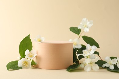 Photo of Beautiful jasmine flowers with leaves on beige background. Space for text