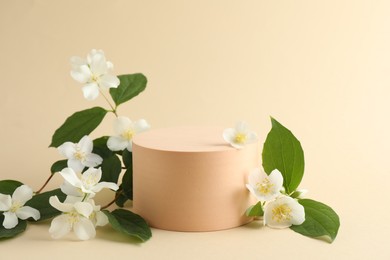 Photo of Beautiful jasmine flowers with leaves on beige background. Space for text