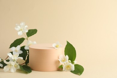 Photo of Beautiful jasmine flowers with leaves on beige background. Space for text