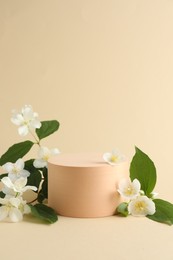 Photo of Beautiful jasmine flowers with leaves on beige background. Space for text