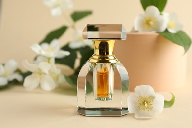 Photo of Bottle of perfume and jasmine flowers on beige background, closeup