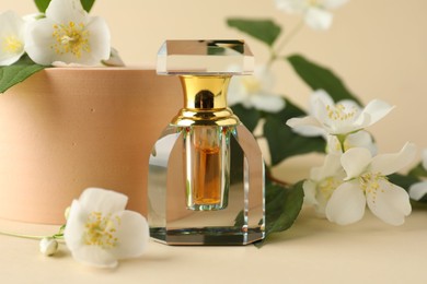 Photo of Bottle of perfume and jasmine flowers on beige background, closeup