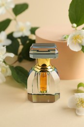 Photo of Bottle of perfume and jasmine flowers on beige background, closeup