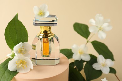 Photo of Bottle of perfume and jasmine flowers on beige background, closeup