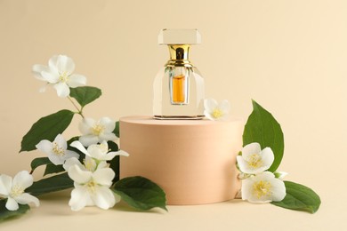 Photo of Bottle of perfume and jasmine flowers on beige background
