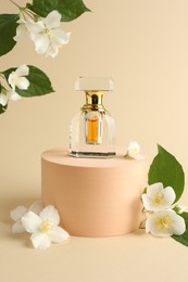 Photo of Bottle of perfume and jasmine flowers on beige background
