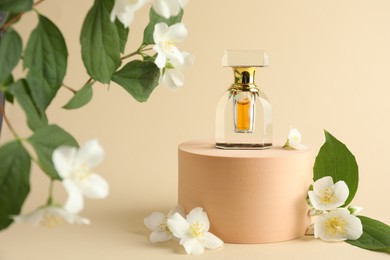 Photo of Bottle of perfume and jasmine flowers on beige background