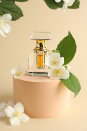 Photo of Bottle of perfume and jasmine flowers on beige background