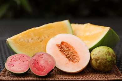 Photo of Ripe juicy tropical fruits on wicker table, closeup