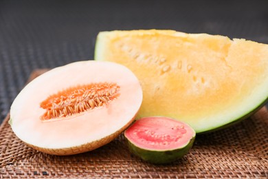 Photo of Ripe juicy tropical fruits on wicker table, closeup