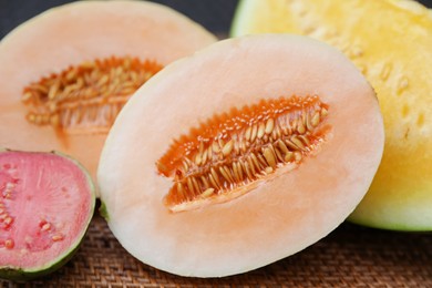 Photo of Ripe juicy tropical fruits on wicker table, closeup