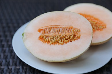 Photo of Halves of juicy melon on wicker table, closeup