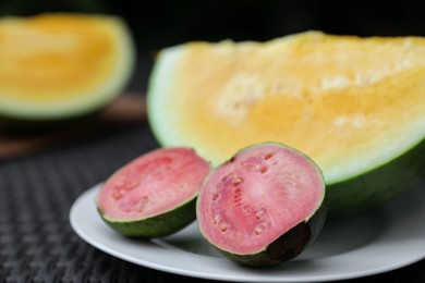 Photo of Ripe juicy tropical fruits on wicker table, closeup