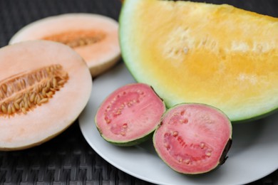 Photo of Ripe juicy tropical fruits on wicker table, closeup