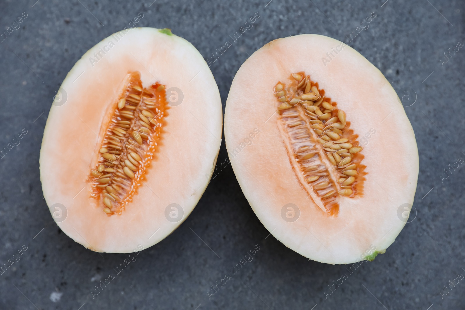 Halves of juicy melon on grey background, top view Photo of Halves of juicy melon on grey background, top view