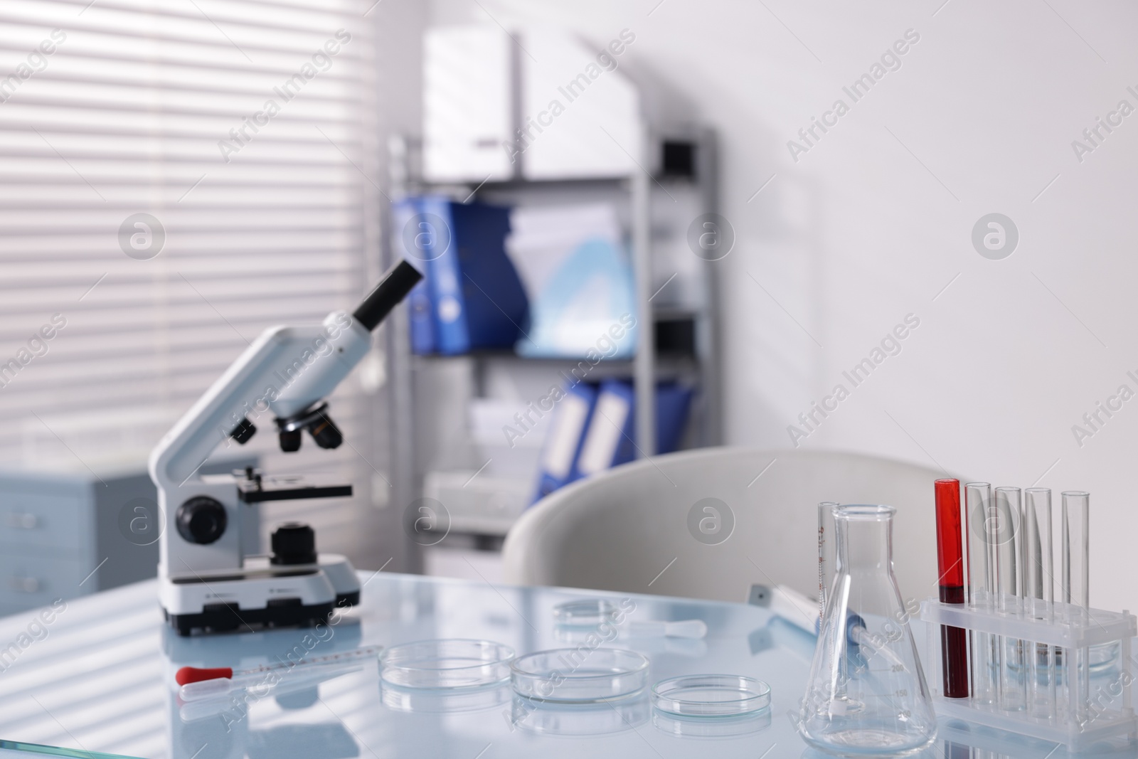 Petri dishes, microscope and test tubes on white table in laboratory Photo of Petri dishes, microscope and test tubes on white table in laboratory