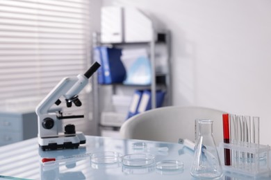 Photo of Petri dishes, microscope and test tubes on white table in laboratory
