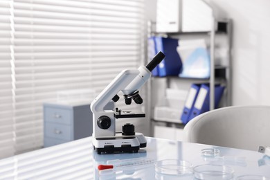 Photo of Petri dishes and microscope on white table in laboratory