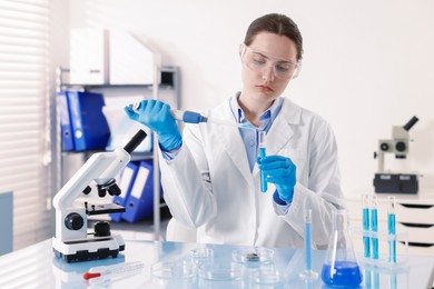 Photo of Scientist working with sample in Petri dish at table in laboratory