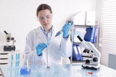 Photo of Scientist working with sample in Petri dish at table in laboratory