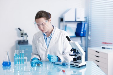 Photo of Scientist working with sample in Petri dish at table in laboratory