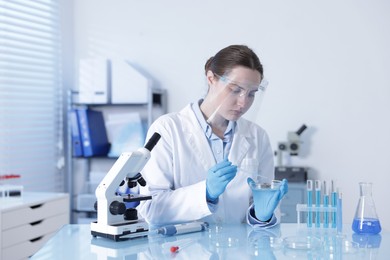Photo of Scientist working with sample in Petri dish at table in laboratory