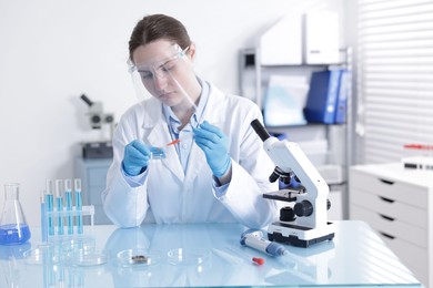 Photo of Scientist working with sample in Petri dish at table in laboratory
