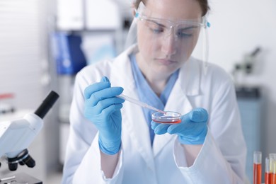 Photo of Scientist working with sample in Petri dish in laboratory, selective focus