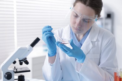 Photo of Scientist working with sample in Petri dish in laboratory
