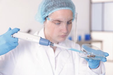 Photo of Scientist working with sample in Petri dish in laboratory, selective focus