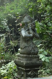 Photo of Bali, Indonesia - May 24, 2025: Beautiful ancient statue and green plants outdoors