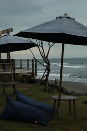 Photo of Bali, Indonesia - May 27, 2025: Bean bag chairs, tables and umbrellas on beach near sea
