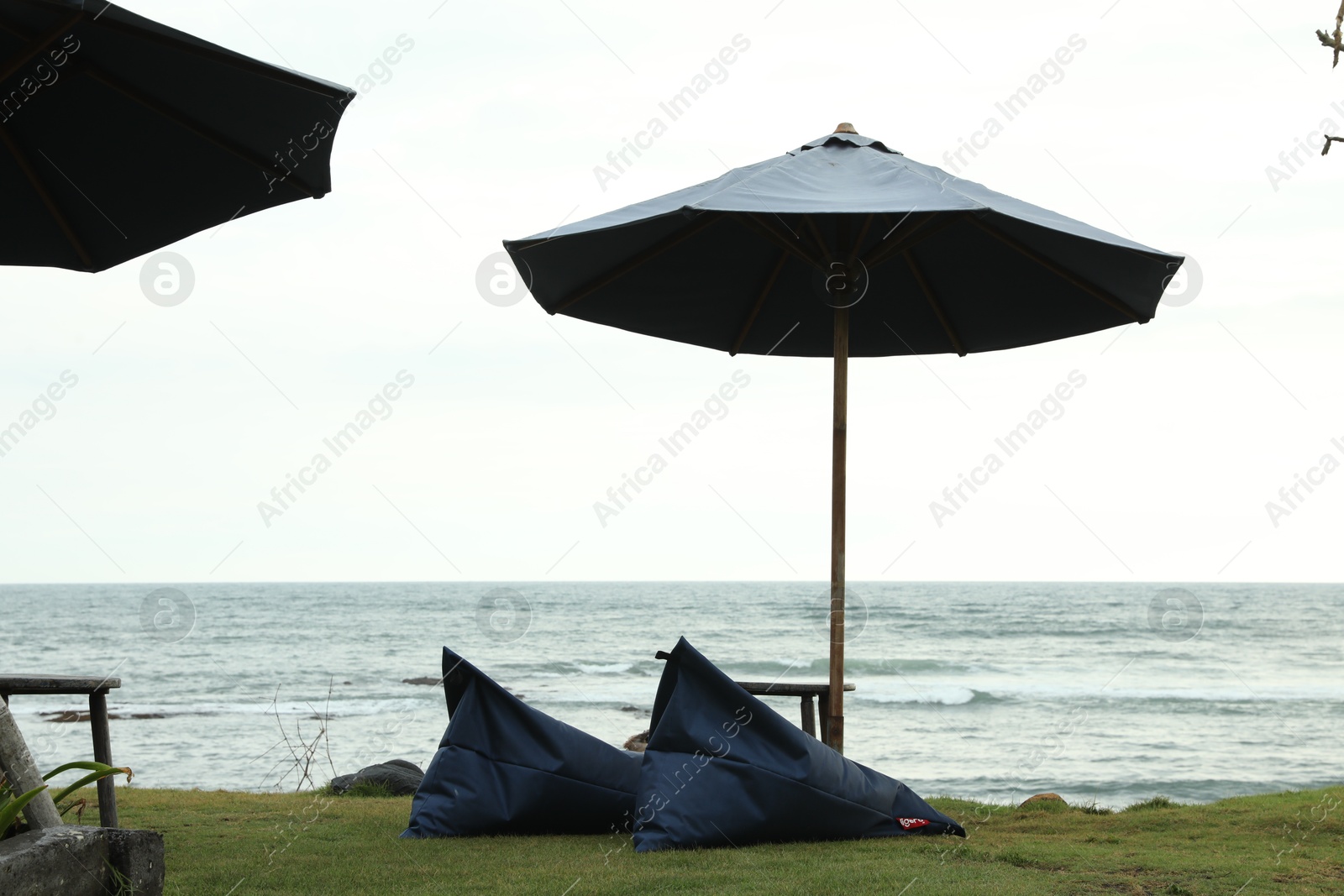 Bali, Indonesia - May 27, 2025: Bean bag chairs, table and umbrella on beach near sea Photo of Bali, Indonesia - May 27, 2025: Bean bag chairs, table and umbrella on beach near sea