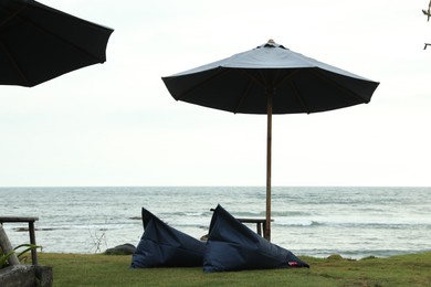 Photo of Bali, Indonesia - May 27, 2025: Bean bag chairs, table and umbrella on beach near sea