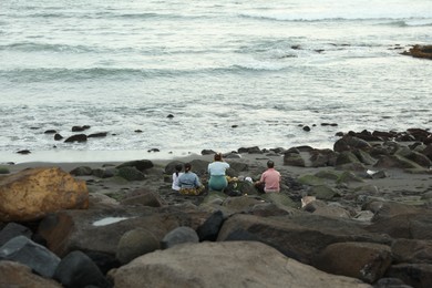 Photo of Bali, Indonesia - May 27, 2025: People resting on rocky beach near sea