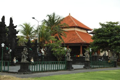 Photo of Bali, Indonesia - May 27, 2025: Beautiful traditional temple with different statues and green trees