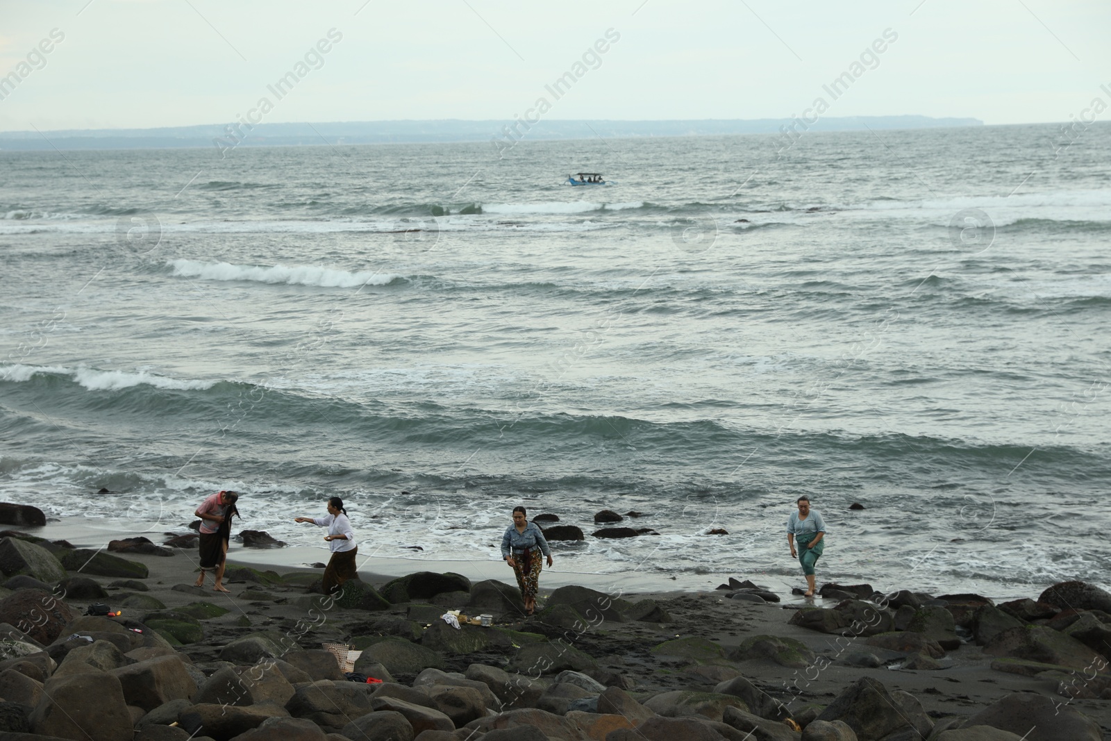 Bali, Indonesia - May 27, 2025: People resting on rocky beach near sea Photo of Bali, Indonesia - May 27, 2025: People resting on rocky beach near sea