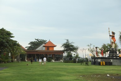 Photo of Bali, Indonesia - May 27, 2025: View of people, statues, cafe and different green plants