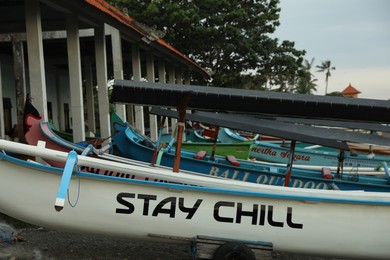 Photo of Bali, Indonesia - May 27, 2025: Different boats near building on sandy beach