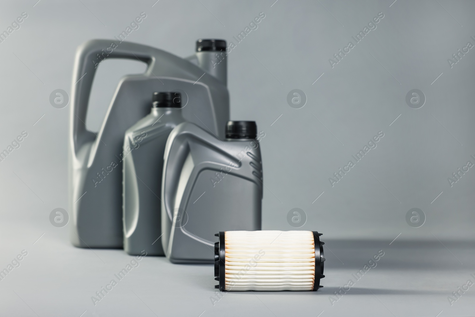 Motor oil in plastic canisters and filter on grey background, selective focus Photo of Motor oil in plastic canisters and filter on grey background, selective focus