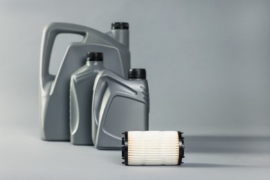 Photo of Motor oil in plastic canisters and filter on grey background, selective focus