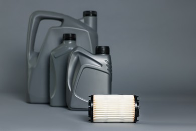 Photo of Motor oil in plastic canisters and filter on grey background, selective focus