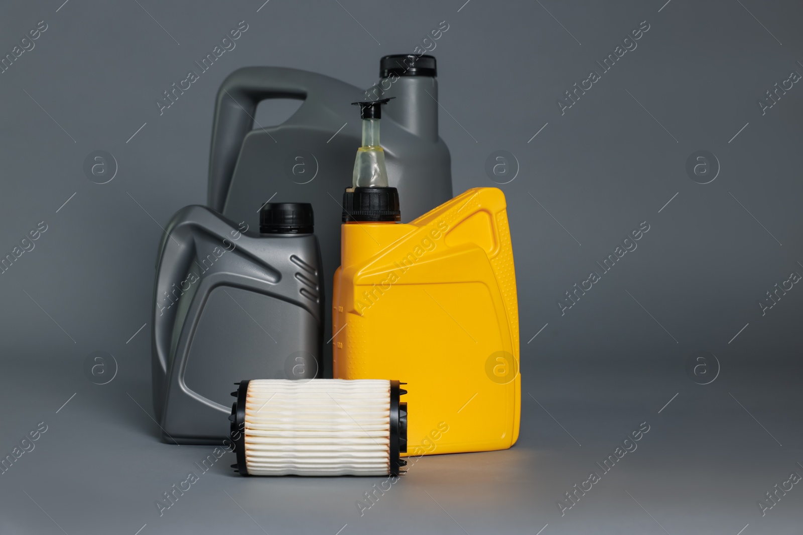 Motor oil in plastic canisters and filter on grey background, space for text Photo of Motor oil in plastic canisters and filter on grey background, space for text