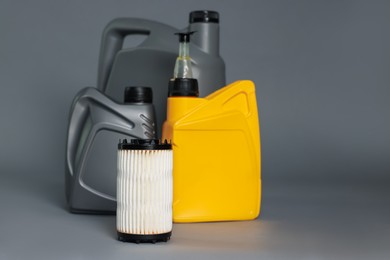 Photo of Motor oil in plastic canisters and filter on grey background, space for text