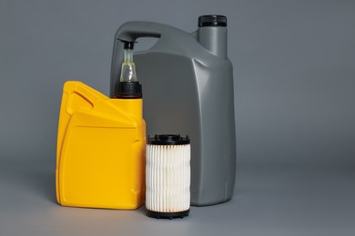 Photo of Motor oil in plastic canisters and filter on grey background, space for text